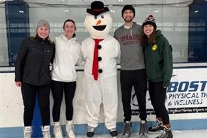 Group photo of four adults with Frosty on the ice
